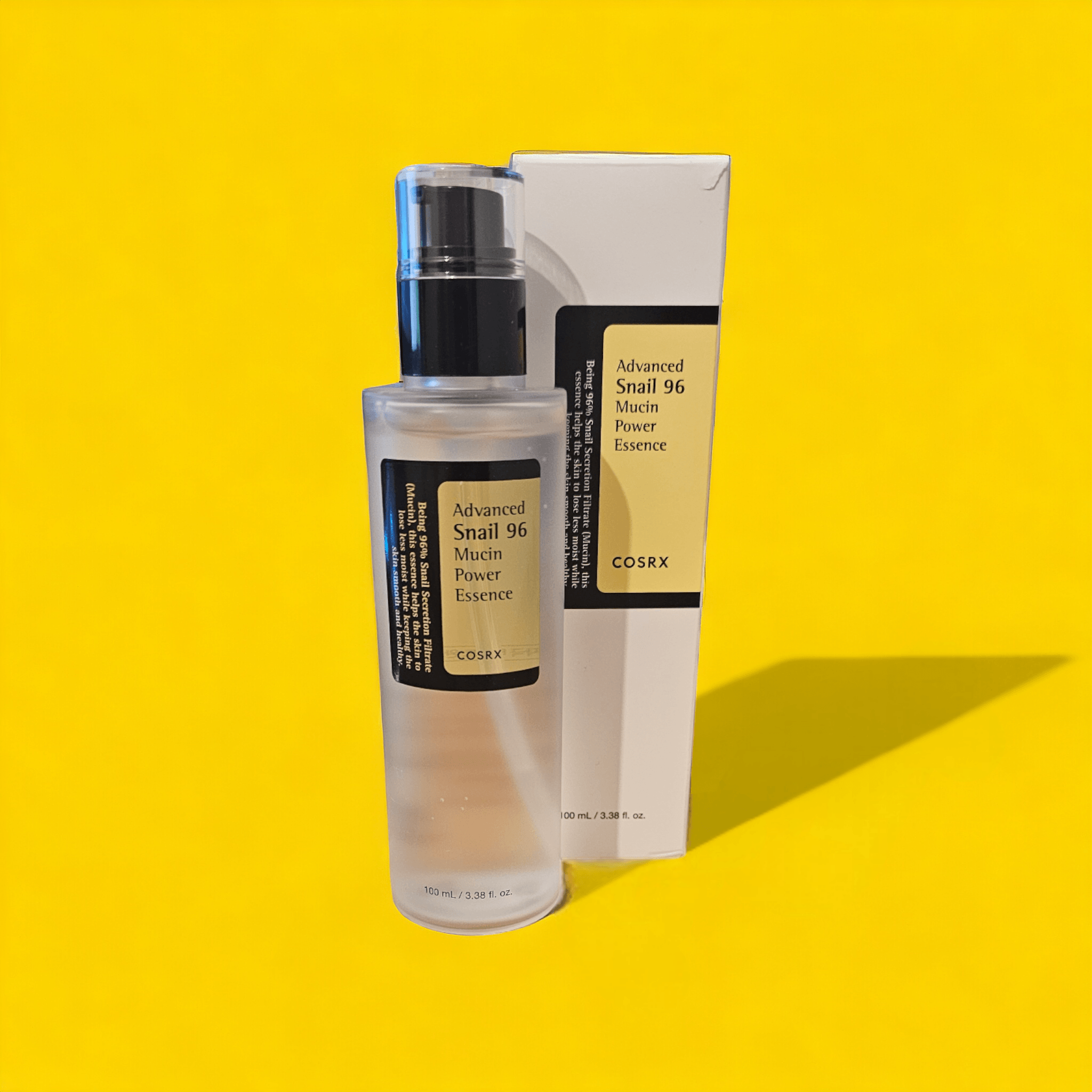 COSRX - Advanced Snail 96 Mucin Power Essence next to its box with a shadow with a yellow background